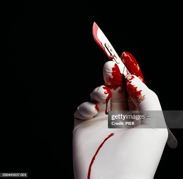 surgeon holding blood stained scalpel, close-up of hand - skalpell stock-fotos und bilder