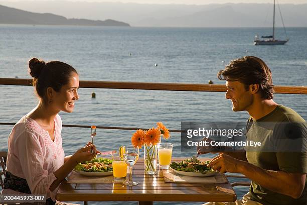couple eating salad at table on deck overlooking sea, side view - dinner on the deck stock pictures, royalty-free photos & images