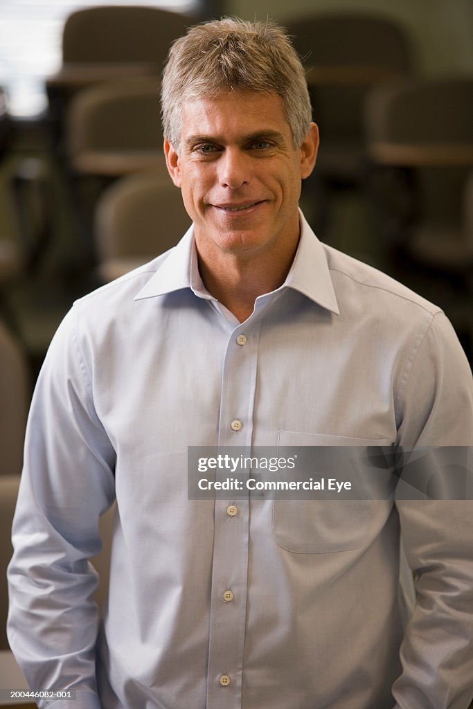 Mature man in classroom smiling, portrait