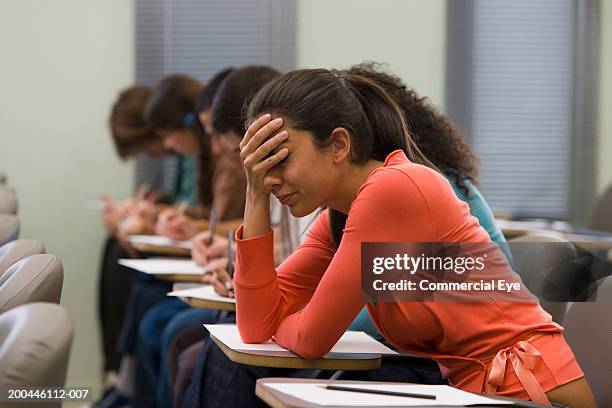students taking written examination, woman holding hand to head - eye exam stockfoto's en -beelden