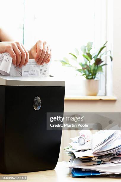 woman shredding receipts in paper shredder, close-up - shredded stockfoto's en -beelden