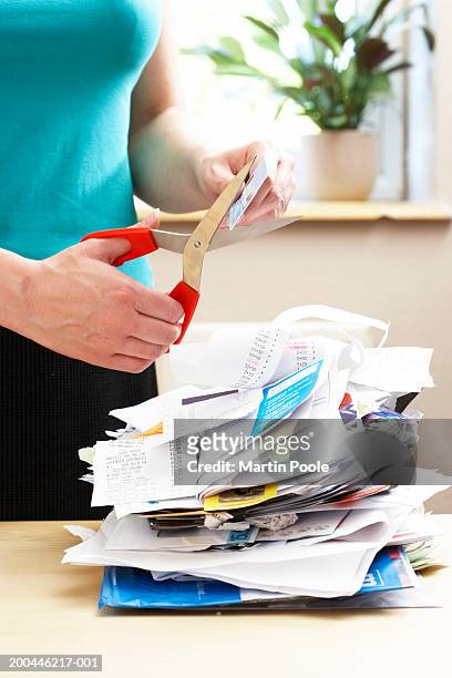 woman cutting credit card over piled receipts and bills, close-up - credit card and stapel stockfoto's en -beelden