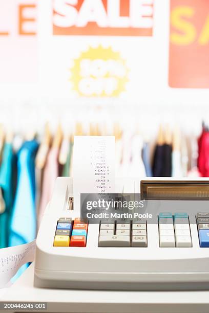long receipt attached to cash register, clothes rail in background - long receipt stock pictures, royalty-free photos & images