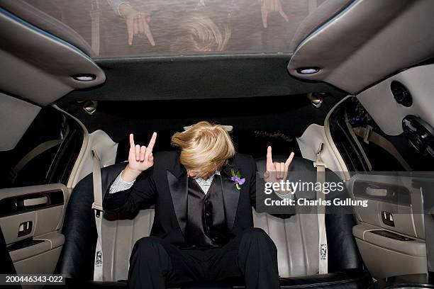 teenage boy (15-17) in tuxedo riding in limousine, gesturing - limousine ストックフォトと画像