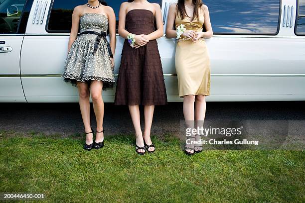 three teenage girls (14-18) in formal dresses beside limo, low section - proms stock-fotos und bilder
