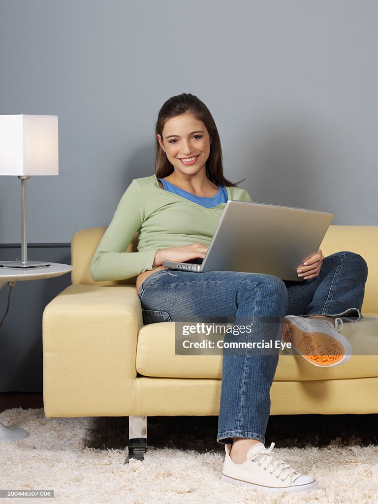 Young woman on sofa, using laptop, portrait