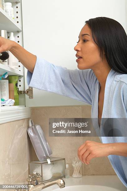 young woman looking in medicine cabinet, side view, close-up - bathroom cabinet stock pictures, royalty-free photos & images