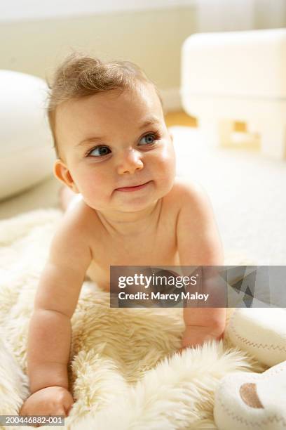 baby girl (6-9 months), looking up from sheepskin rug - sheepskin stock pictures, royalty-free photos & images