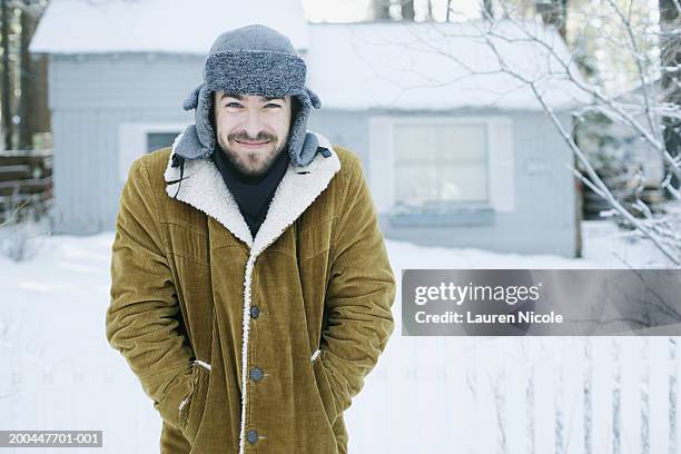 young man standing outdoors in snow, smiling, portrait - hunters cap stock pictures, royalty-free photos & images