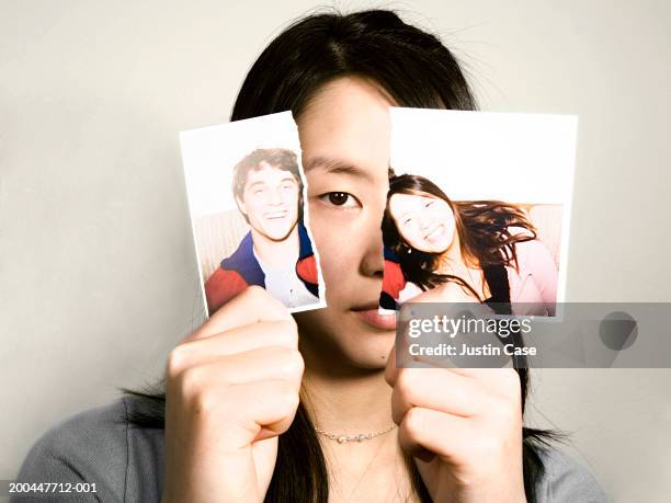 teenage girl (15-17) holding up torn photograph, portrait, close-up - torn photograph stock pictures, royalty-free photos & images