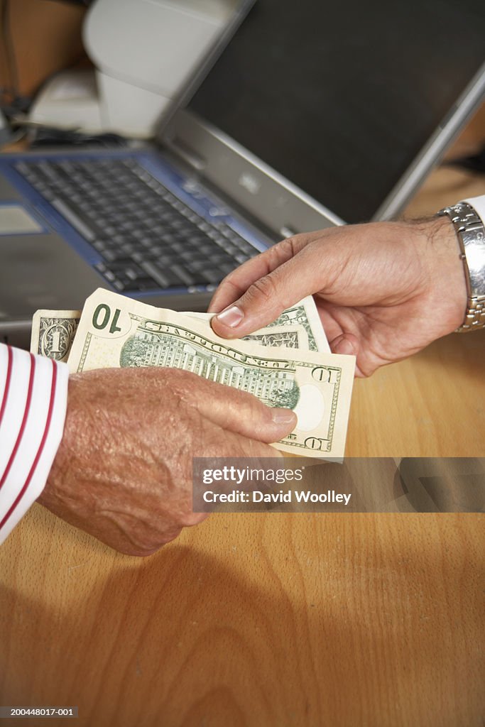 Senior man handing another man banknotes, close-up