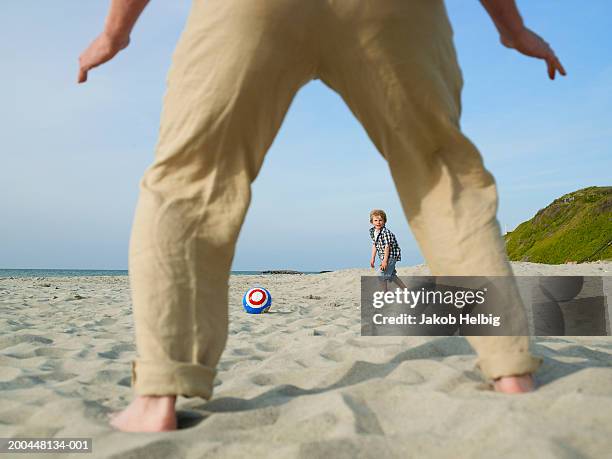 grandfather playing football on beach with grandson (4-6), low section - barefeet soccer stock pictures, royalty-free photos & images