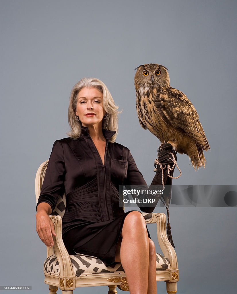Woman holding Eurasian Eagle Owl (Bubo bubo), sitting, portrait