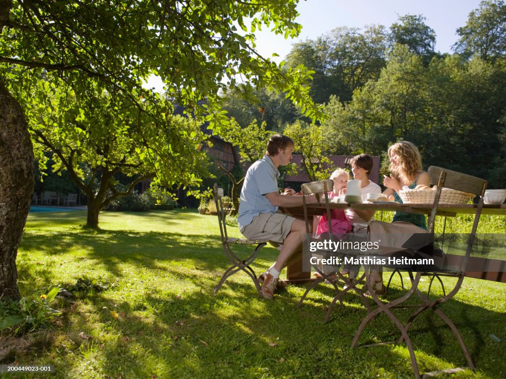 Family having breakfast in garden with daughter (3-5) smiling