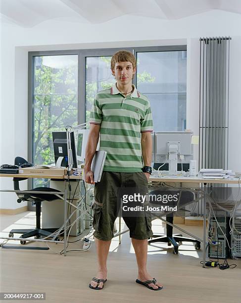 casually dressed young male office worker, holding laptop, portrait - shorts ストックフォトと画像