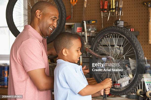 father and son (57) fixing bicycle in garage - tuerca fotografías e imágenes de stock