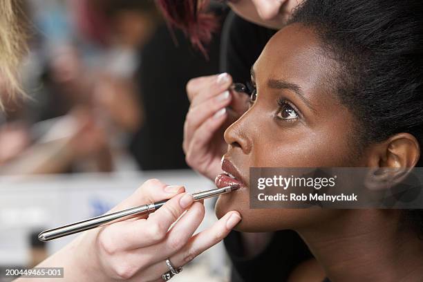 makeup artists applying makeup to female model's eyes and lips - woman backstage stock pictures, royalty-free photos & images