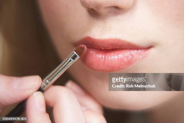 makeup artist applying lipstick to girl's (16-18) lips, close-up - visagist stockfoto's en -beelden