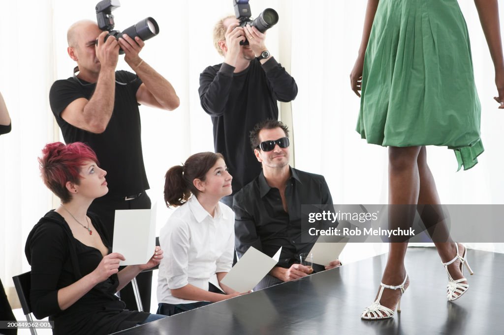 Photographers and spectators watching model on runway at fashion show