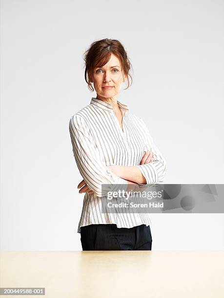 mature woman standing behind desk, arms folded, portrait - folded blouse stock pictures, royalty-free photos & images