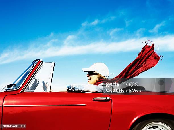 young woman driving red convertible car, side view - convertible stock pictures, royalty-free photos & images