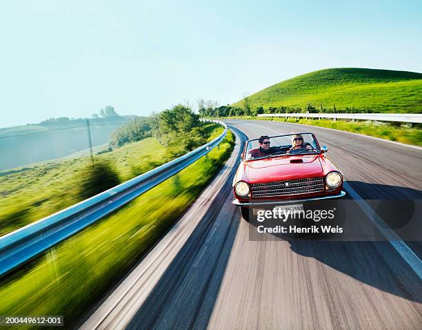 young couple driving convertible car in countryside (blurred motion) - convertible car fotografías e imágenes de stock