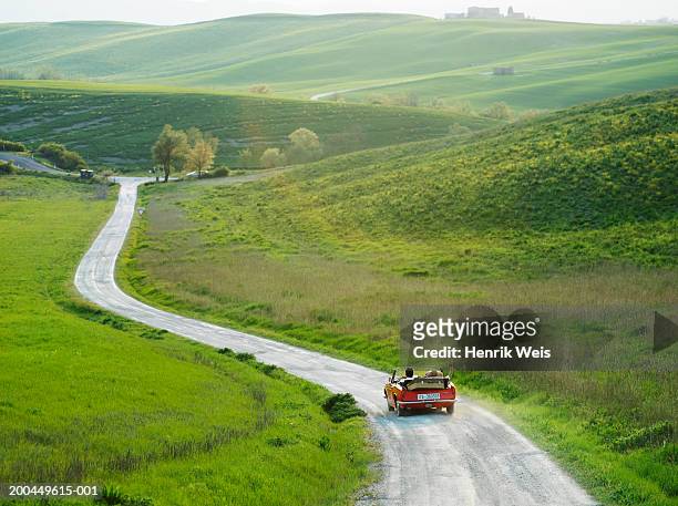 young couple driving convertible car in countryside, rear view - on the move rear view stockfoto's en -beelden