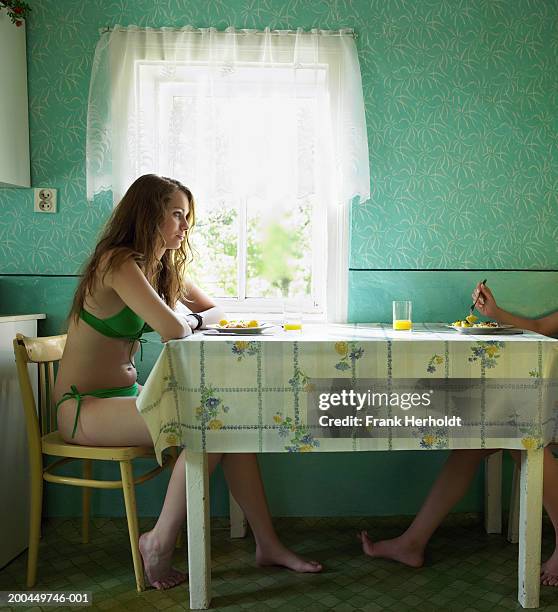 young woman wearing bikini, sitting at table, side view - young women no clothes stock pictures, royalty-free photos & images