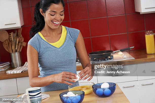 woman in kitchen breaking eggs into bowl, smiling - omelette stock pictures, royalty-free photos & images