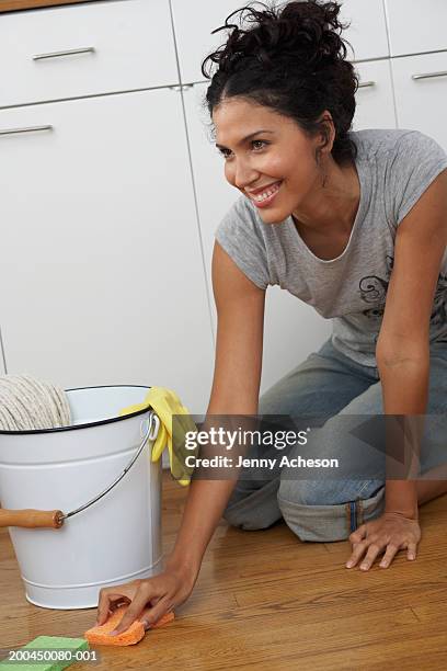 young woman kneeling to clean floor, smiling - daily bucket stock pictures, royalty-free photos & images