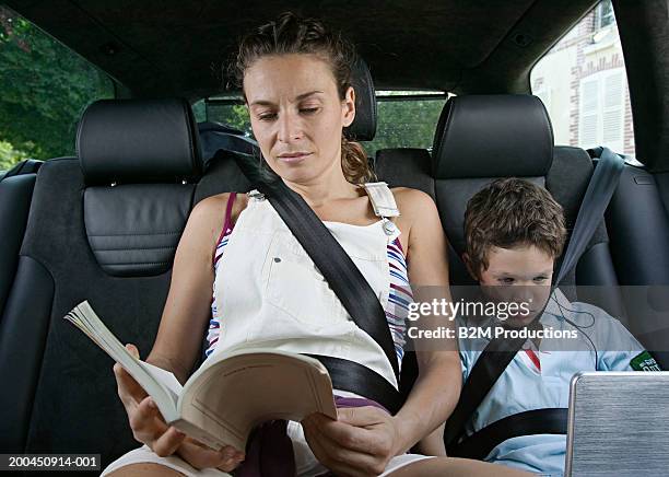 mother reading book in car, son (4-6) watching portable dvd player - dvd player in car stock pictures, royalty-free photos & images