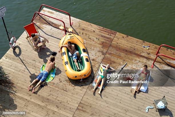 five friends sunbathing on pier by lake, elevated view - bote neumático fotografías e imágenes de stock