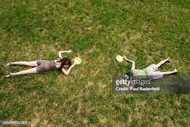 young couple lying on grass holding raquets, elevated view - crazy girlfriend stock pictures, royalty-free photos & images