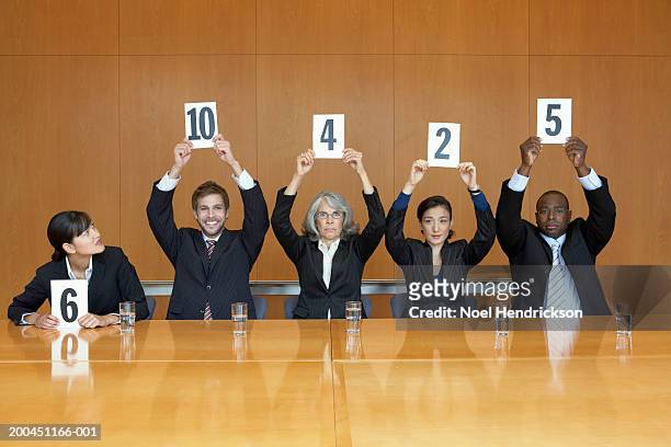business colleagues holding up cards with numbers - scoring stockfoto's en -beelden