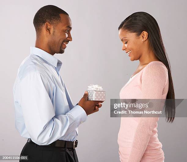 young man giving gift to young woman, side view - no tie stock pictures, royalty-free photos & images