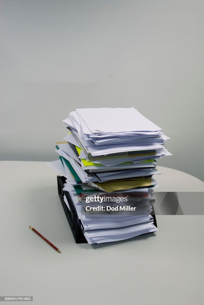 Pencil on table beside stack of files, elevated view