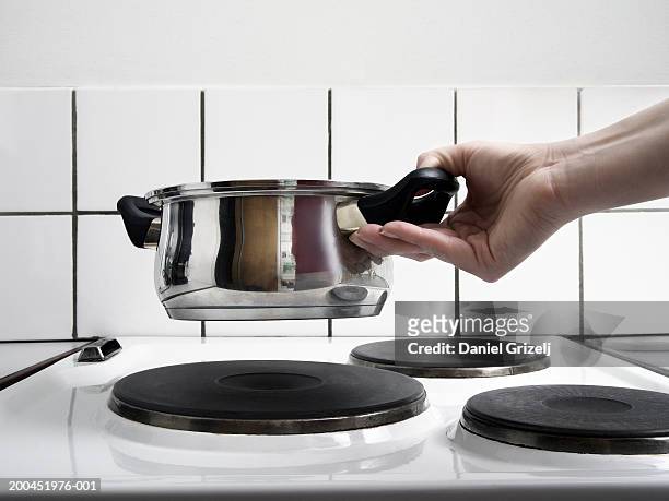woman holding saucepan over stove, close-up - electric stove burner ストック��フォトと画像
