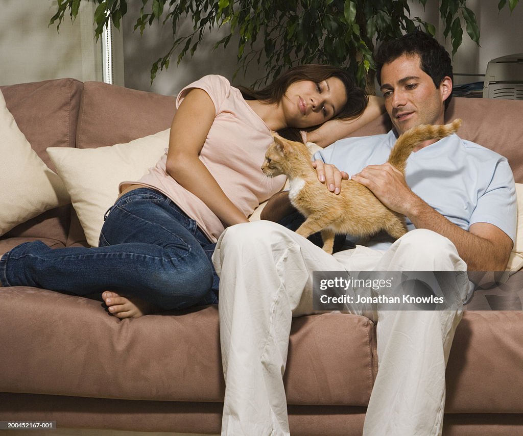 Couple sitting on sofa with cat