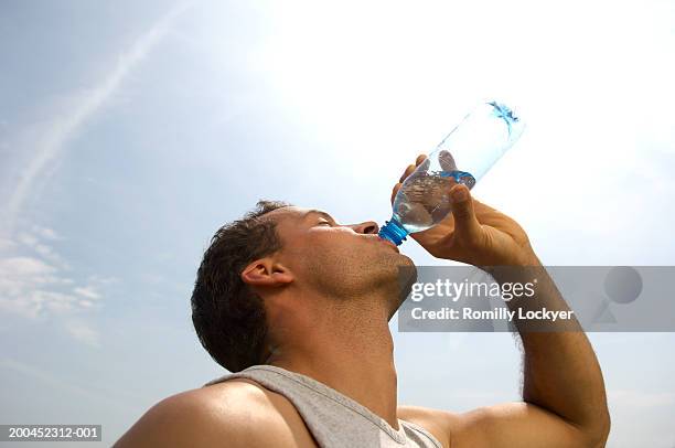 man drinking from water bottle outdoors, low angle view - bere foto e immagini stock