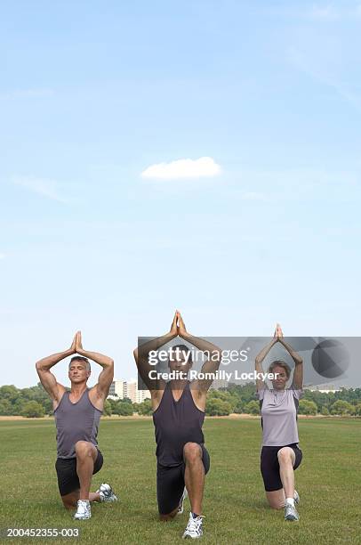 three friends practising yoga in park - richmond upon thames stockfoto's en -beelden