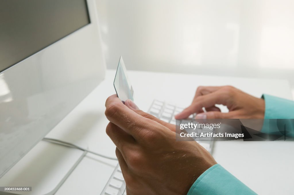 Man using credit card for online transaction, close-up