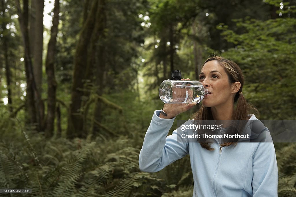Woman drinking water in forest