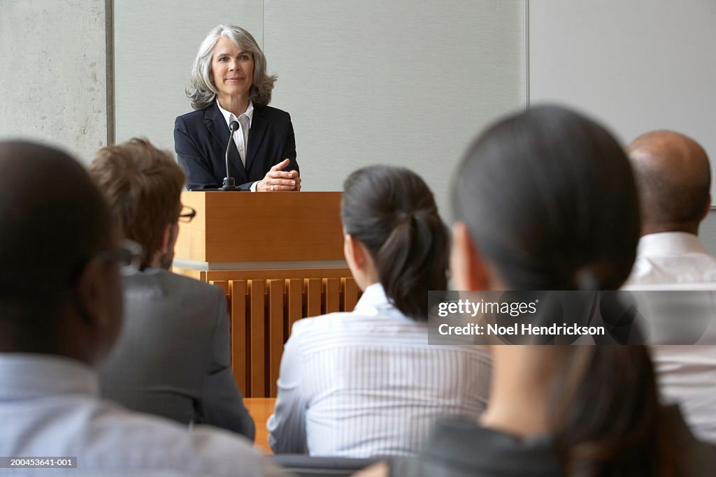 Businesswoman at podium talking to colleagues