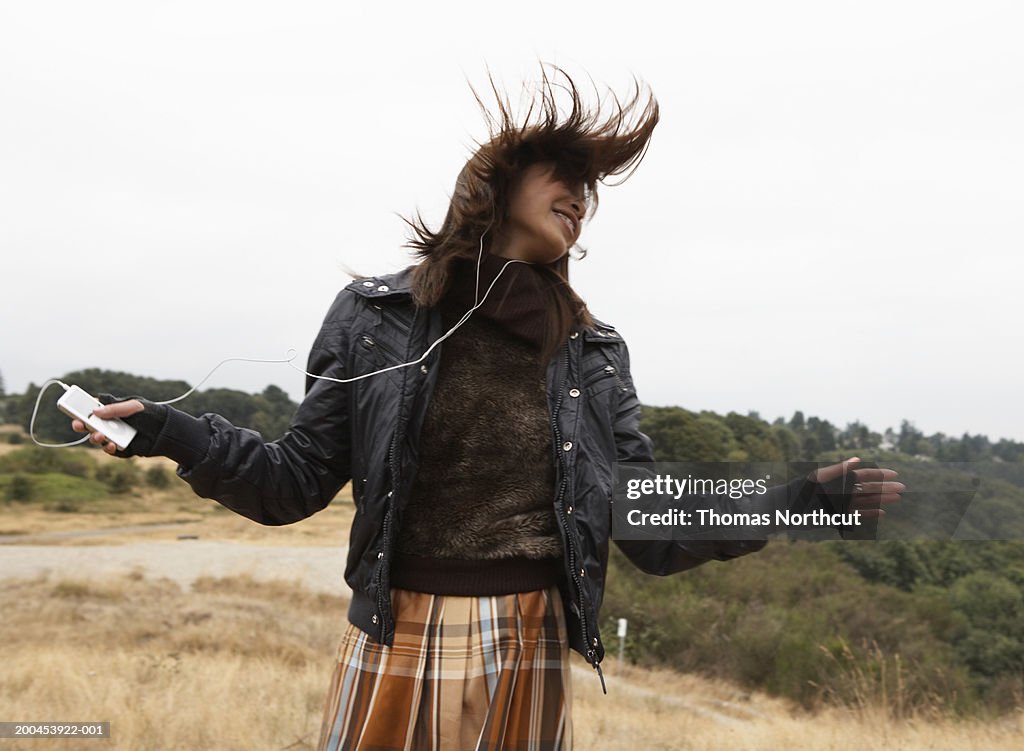 Teenage girl (15-17) listening to MP3 player, dancing (blurred motion)