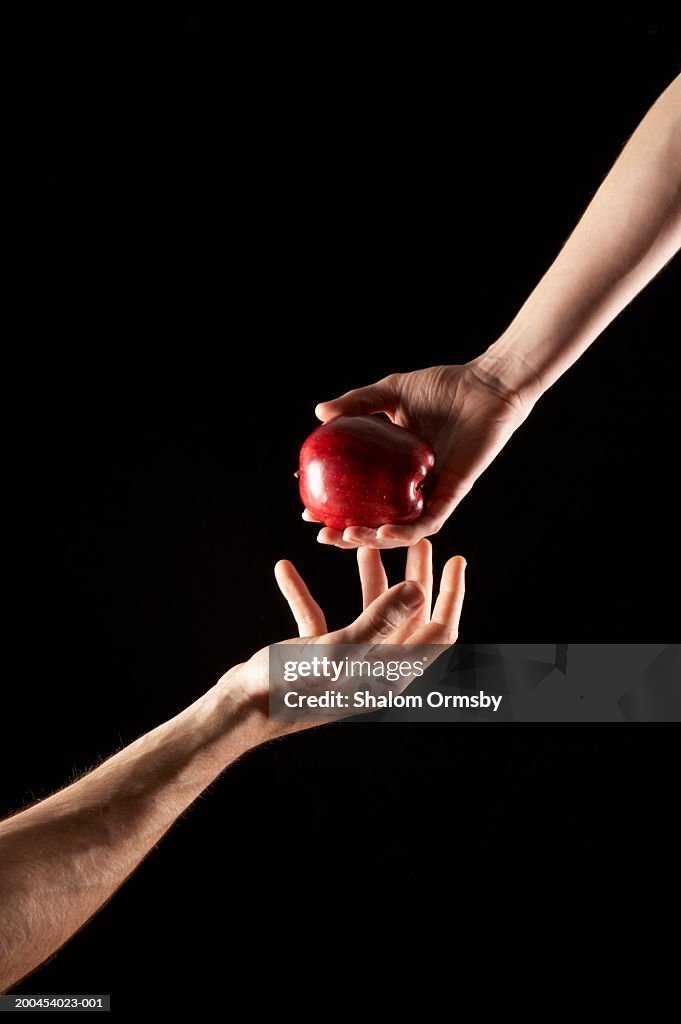 Hand passing apple to another hand