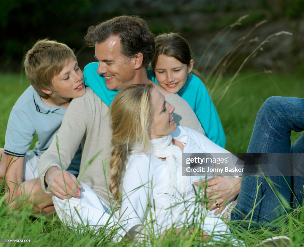 Family sitting in field, smiling