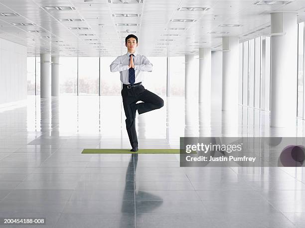 businessman doing tree pose in empty office space - office yoga stock pictures, royalty-free photos & images