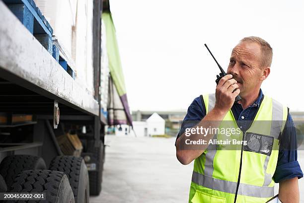 man standing by lorry using walkie-talkie - security guard stock-fotos und bilder