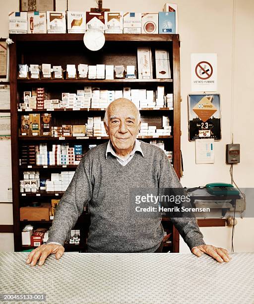 senior man behind counter in tobacconists, portrait - tobacco product stock photos et images de collection