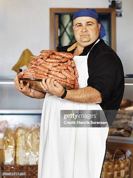 male butcher holding tray of sausages, portrait - boucher photos et images de collection